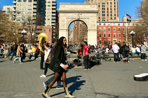 Young woman walking through Washington Square Park with Washington Square Arch in background